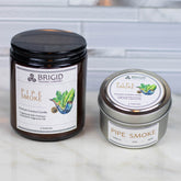 pipe smoke premium soy wax candle gifts by brigid trading company tobacco smoke oud wood and musk original photography by brigid trading company llc kitsap county washington state usa natural and handmade masculine woodsy woody scent celtic themed irish roots photo shows a light marble background with light marble foreground and two candles one amber glass jar candle one tin small container candle